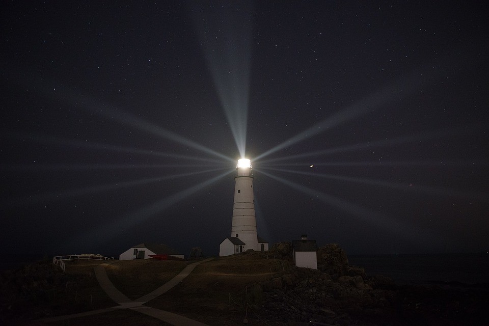 A Maine lighthouse casting beams across the night sky
